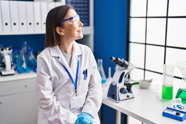 Middle age woman scientist smiling confident at laboratory - Foto, immagini