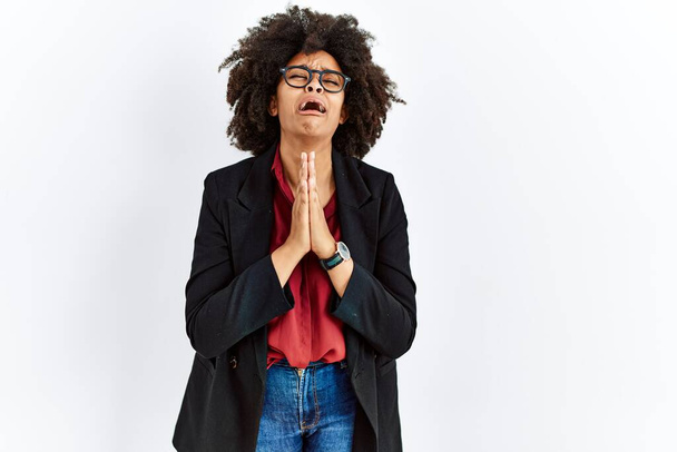 African american woman with afro hair wearing business jacket and glasses begging and praying with hands together with hope expression on face very emotional and worried. begging.  - Photo, Image