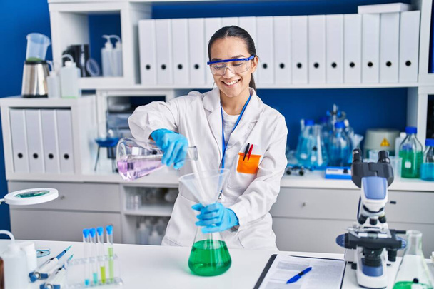 Nuori latino nainen tiedemies mittaus nestettä laboratoriossa - Valokuva, kuva