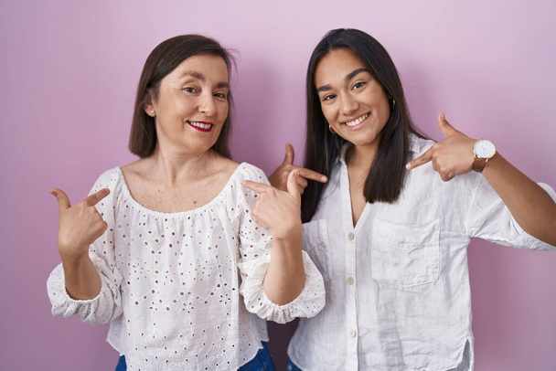 Hispanic mother and daughter together looking confident with smile on face, pointing oneself with fingers proud and happy.  - Photo, Image