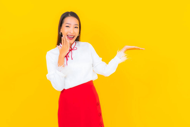 Retrato hermosa joven mujer asiática sonrisa en acción sobre fondo amarillo - Foto, imagen