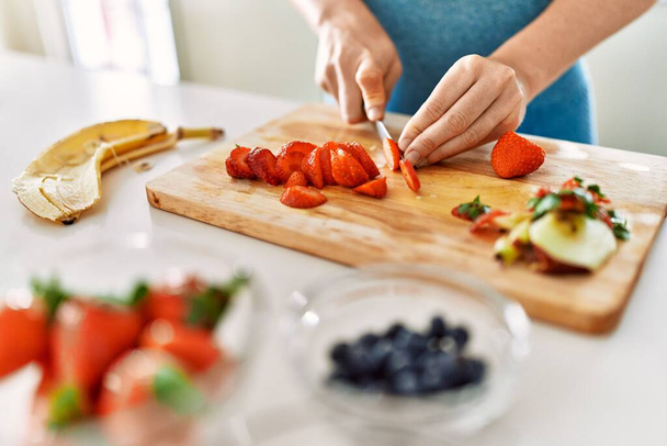 Young woman cutting strawberry at kitchen - Фото, изображение