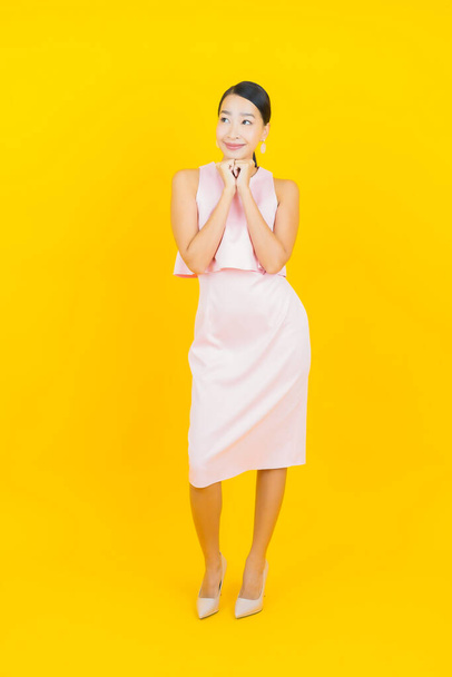 Retrato hermosa joven mujer asiática sonrisa con acción sobre fondo de color amarillo - Foto, imagen