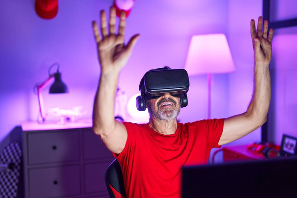 Homme moyen streamer jouer à un jeu vidéo en utilisant des lunettes de réalité virtuelle à la salle de jeux - Photo, image