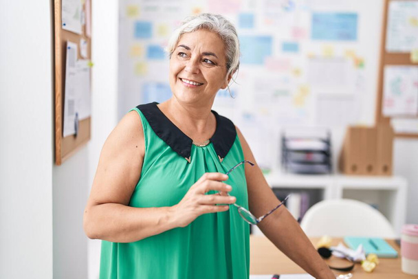 Седовласая деловая женщина средних лет, уверенно улыбающаяся в офисе - Фото, изображение