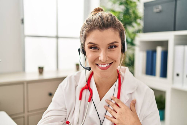 Young blonde woman wearing doctor uniform having teleconsultation at clinic - Photo, image