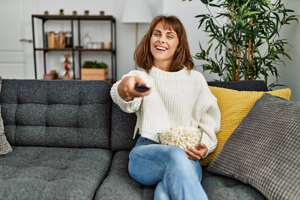 Young caucasian woman watching movie sitting on sofa at home - Photo, Image