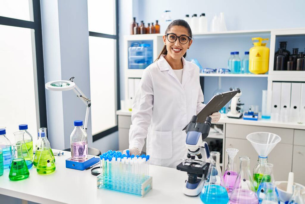 Laboratuvarda çalışan, bilim adamı üniforması giyen genç İspanyol kadın. - Fotoğraf, Görsel