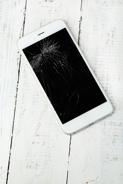 Broken iPhone on wooden background - Fotoğraf, Görsel