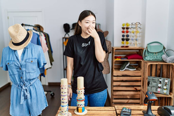 小売店のマネージャーとして働いている若いアジアの女性は、臭いと嫌な、耐えられない匂いを嗅ぎ、鼻の上に指で息をしています。臭いが悪い  - 写真・画像