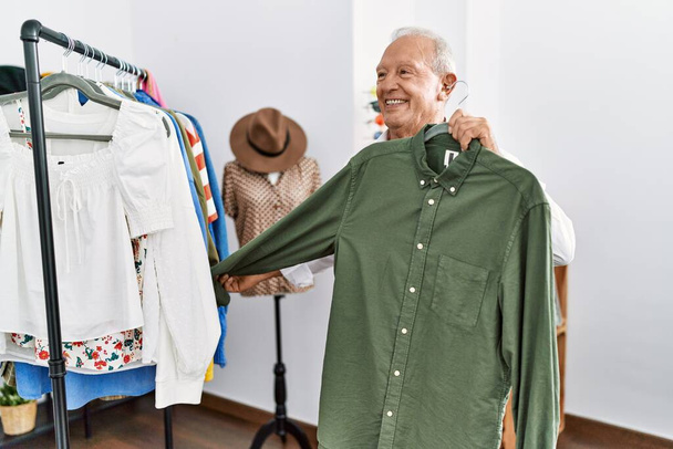 Senior man klant houdt shirt in de kledingwinkel - Foto, afbeelding