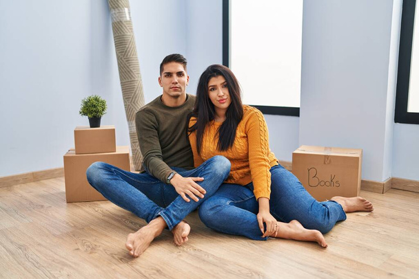 Nuori pari istuu lattialla uudessa kodissa rento vakava ilme kasvoilla. yksinkertainen ja luonnollinen kameraan katsominen.  - Valokuva, kuva