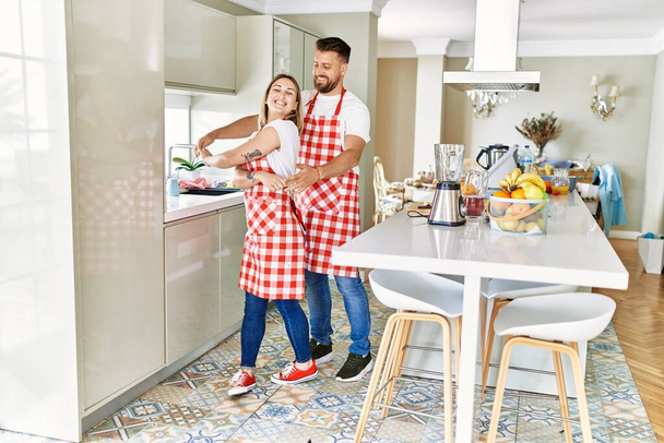 Молодая пара улыбается уверенно танцуя на кухне - Фото, изображение