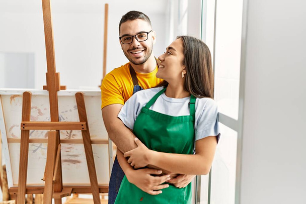 Young hispanic couple smiling happy and hugging at art studio. - Foto, immagini
