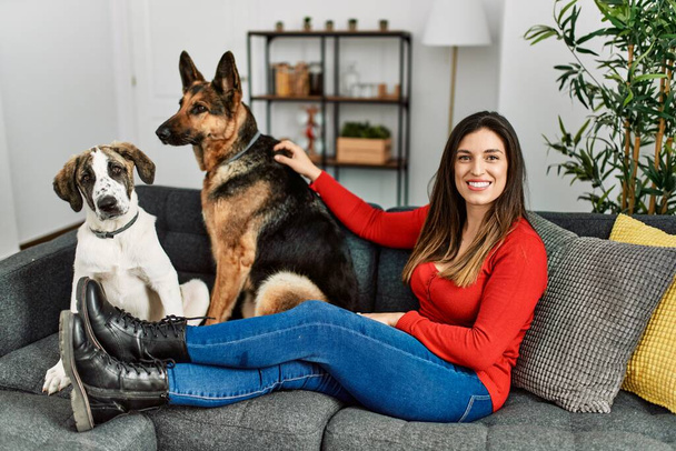 Young woman smiling confident sitting on sofa with dogs at home - Foto, Imagen