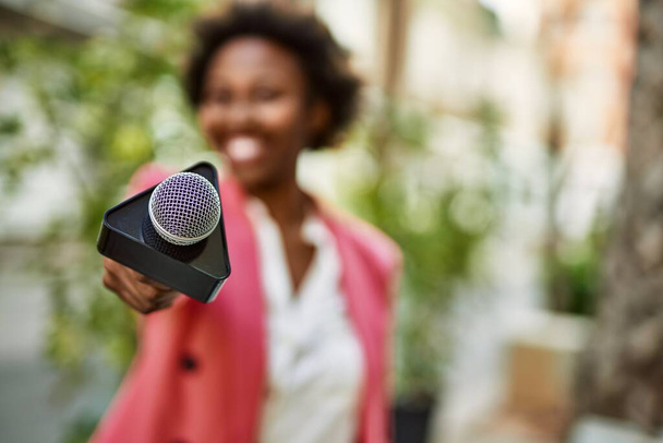 Jeune journaliste afro-américaine pointant le microphone du journaliste vers la caméra pour les nouvelles de la télévision - Photo, image