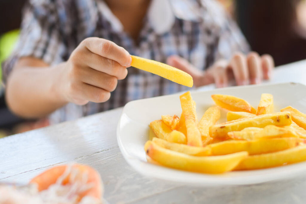 child eating french fries or potato chips. - Foto, Imagem