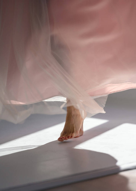 The legs of a girl and a delicate dress swirling in the light. - Фото, изображение