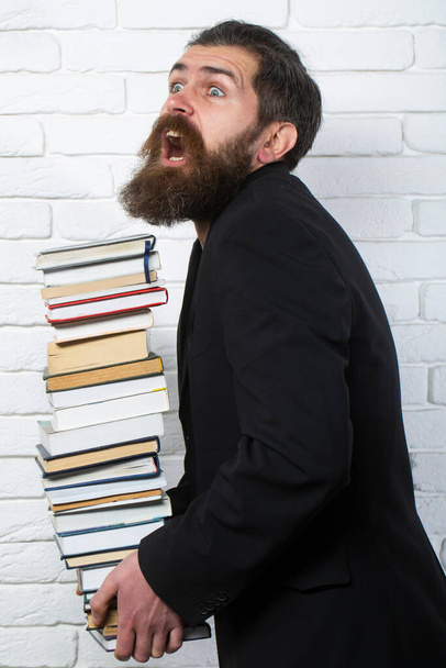 Funny teacher or professor with book stack. Thinking serious mature teacher. Falling books concept. Mature professor, middle aged teacher, bearded fun man. Books stacked fall - Zdjęcie, obraz