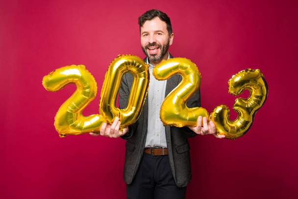 Entusiasmado homem bonito segurando 2023 balões para celebrar a festa de ano novo - Foto, Imagem