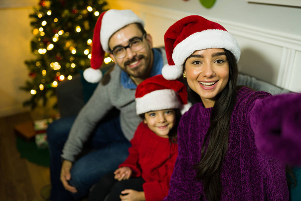 Prospettiva personale di una famiglia felice che si fa un selfie dopo aver messo l'albero di Natale a casa - Foto, immagini