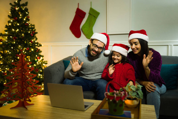 陽気な両親とともに彼らの小さな娘持っていますビデオ通話と家族や友人とクリスマスの夜 - 写真・画像