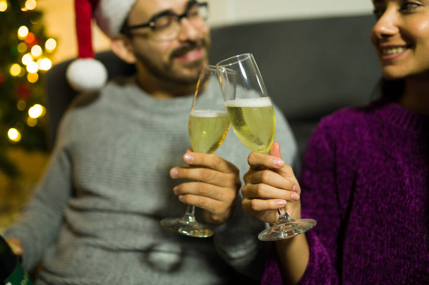 Close up de um casal segurando duas flautas de champanhe tostando durante as férias de Natal - Foto, Imagem