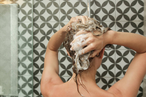 Junge Frau duscht und wäscht sich in Duschkabine die Haare. - Foto, Bild