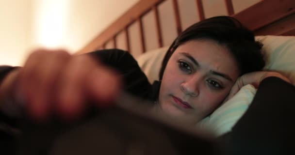 Young woman in bed with smartphone. Woman starring at cellphone device before going to bed - Footage, Video