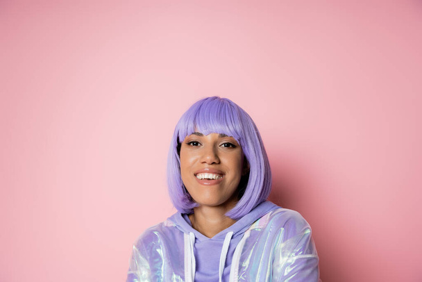 happy african american woman in purple wig smiling isolated on pink  - Фото, изображение