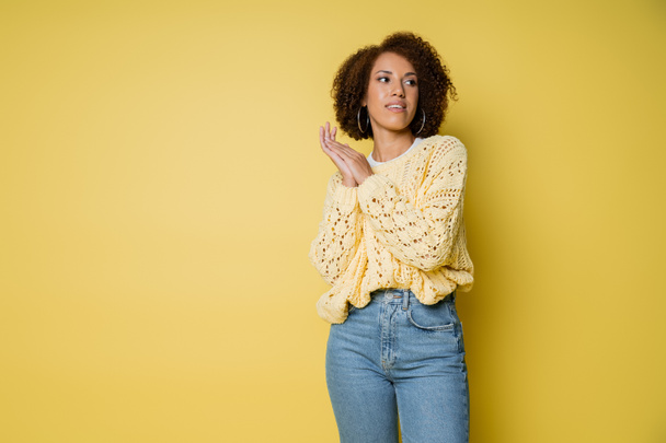 dreamy and young african american woman in knitted sweater on yellow - Фото, зображення