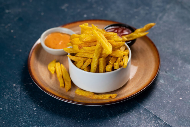 Knusprige Pommes frites oder Kartoffelchips mit Mayo-Dip und Tomatensauce serviert in einem Teller Seitenansicht - Foto, Bild