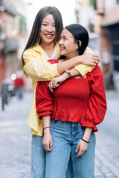 Young asian woman having fun in the city of Madrid hugging her friend and looking at camera. - Valokuva, kuva