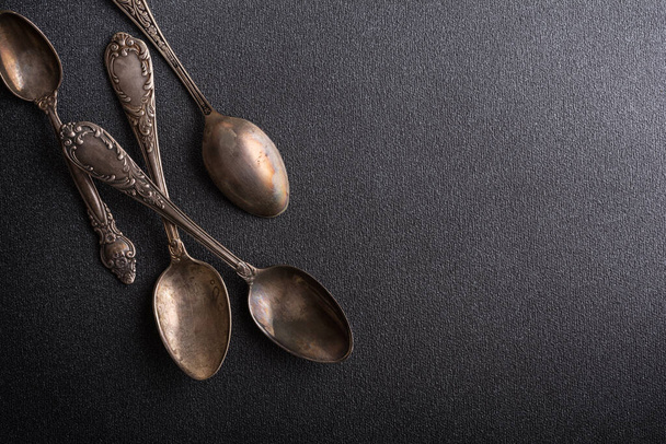 Top view of vintage silver spoons or silverware on dark concrete background with copy space - Fotó, kép