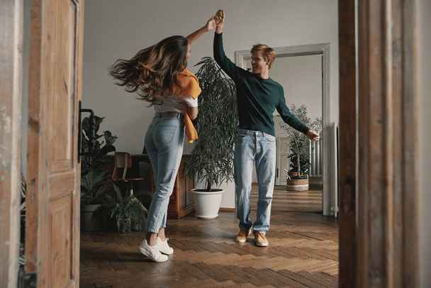 Full length of beautiful young couple dancing and smiling at home together - Photo, image