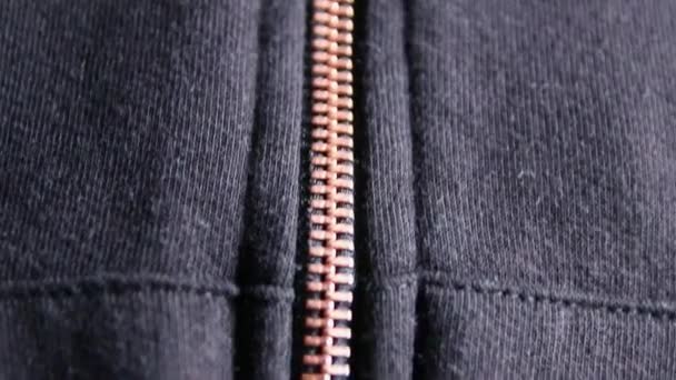 φερμουάρ μόδας χρώματος χαλκού σε γκρο πλαν προβολή που δείχνει μαύρο φούτερ με μερικό ανοιγμένο μεταλλικό φερμουάρ με μαύρο ύφασμα σε μεταλλικό οπτικό ως κομψό ένδυμα ή κομψό συνδετήρα στερεό υλικό - Πλάνα, βίντεο