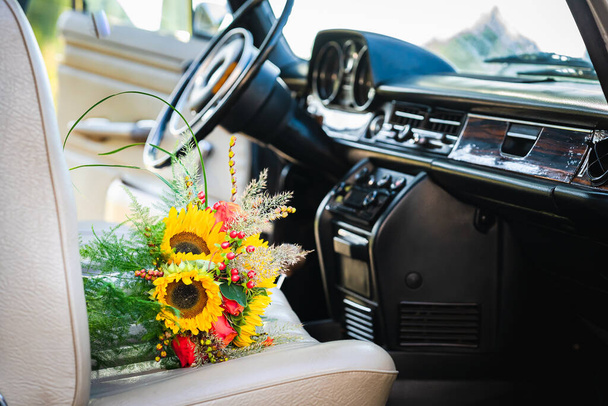 Oldtimer Hochzeitsauto mit reizendem Brautstrauß voller Rosen und Sonnenblumen - Foto, Bild