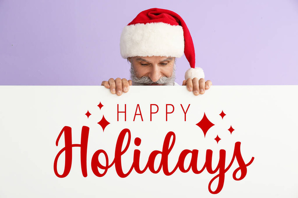 Santa Claus and poster with text HAPPY HOLIDAYS on lilac background - Valokuva, kuva