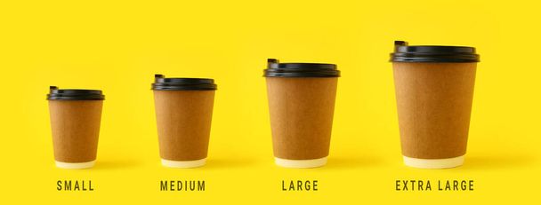 Different sized takeaway coffee cups on yellow background - Photo, Image