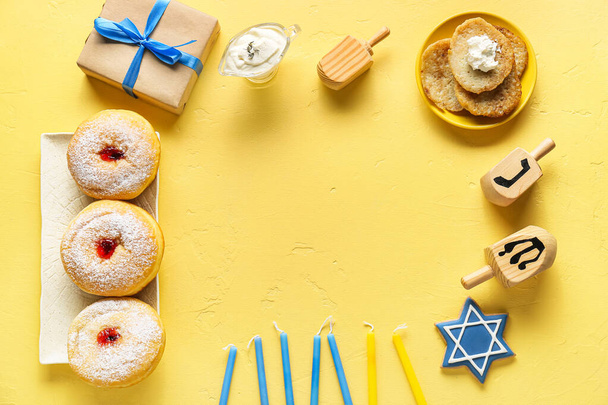 Keret készült gyertyák, fa dreidels, ajándék doboz és élelmiszer Hanuka ünneplés színes háttér - Fotó, kép