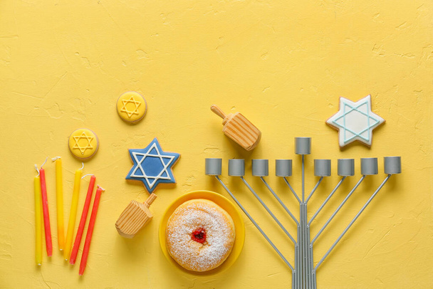 Összetétel menóra, gyertyák, fa dreidels és élelmiszer Hanuka ünneplés színes háttér - Fotó, kép