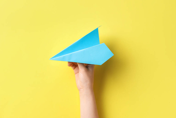Woman with blue paper plane on yellow background - Foto, Imagen