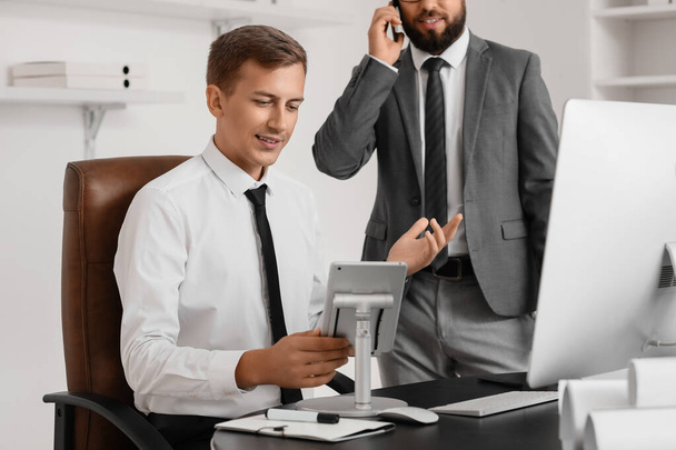 Young bank manager working with tablet computer at table in office - Photo, Image