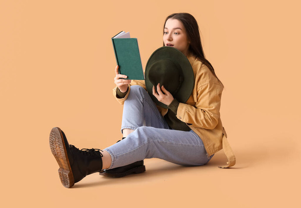 Junge Frau mit Hut liest Buch auf beigem Hintergrund - Foto, Bild