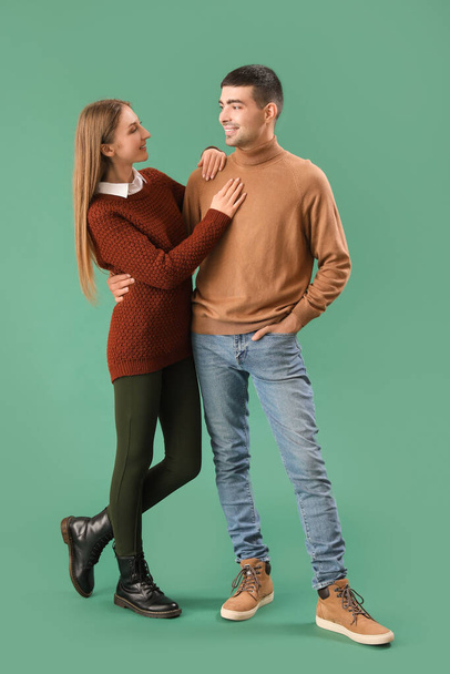Fashionable young couple in autumn clothes on green background - Foto, afbeelding