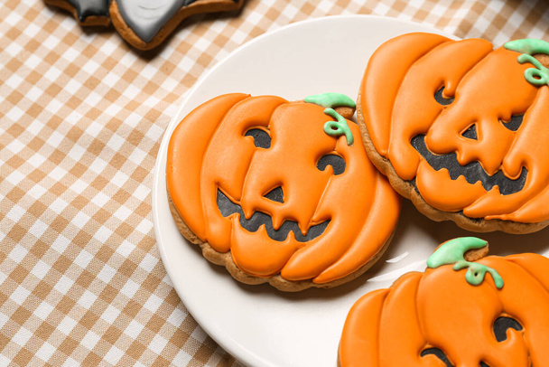Plate with Halloween pumpkin cookies on checkered napkin, closeup - Photo, Image