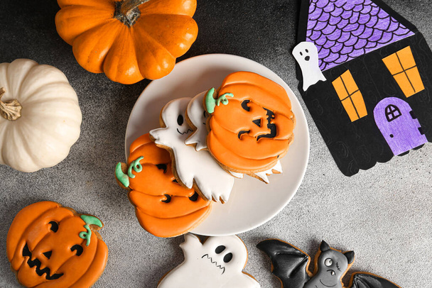 Plate with Halloween cookies, pumpkins, paper house on black and white background - Photo, Image