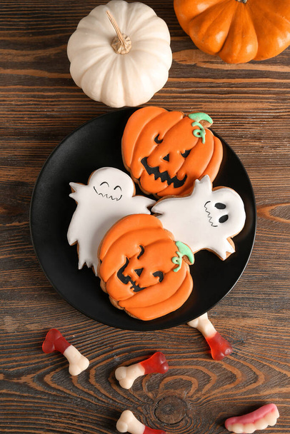 Plate with tasty Halloween cookies and jellies on wooden background - Photo, Image