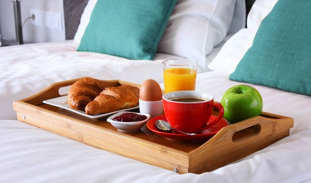 Śniadanie na tacy w łóżku w pokoju hotelowym.  - Zdjęcie, obraz