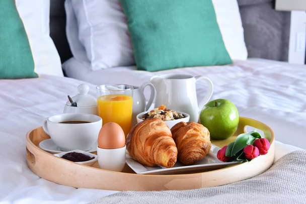Frühstück auf Tablett im Bett im Hotelzimmer.  - Foto, Bild